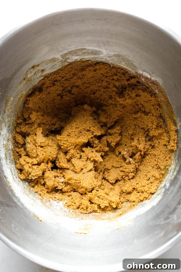 Thick vegan gingerbread dough forming in a mixing bowl.