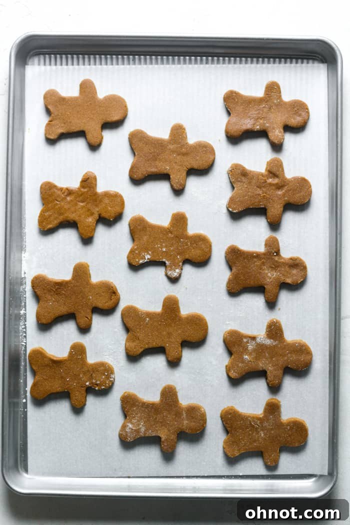 Gingerbread men cookies arranged on a baking sheet, ready for the oven.