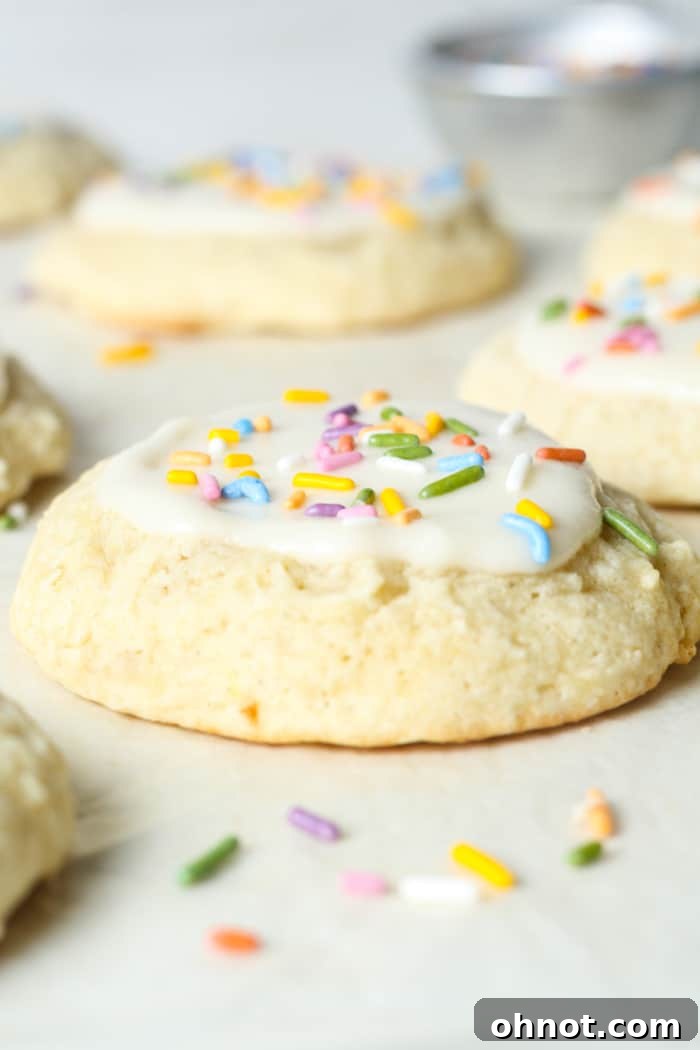 A stack of soft baked sour cream sugar cookies on a cooling rack, some plain and some frosted.
