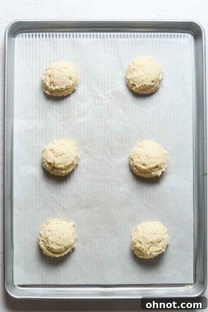 Uniform scoops of cookie dough neatly arranged on a parchment-lined baking pan.
