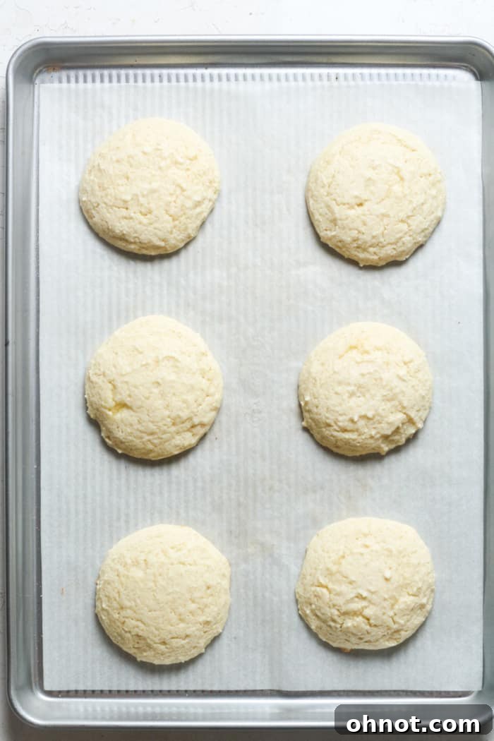 Thick, freshly baked cookies cooling on a baking sheet.