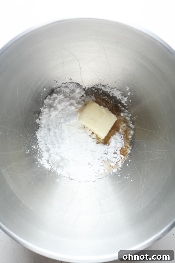 Ingredients for buttercream frosting in a mixing bowl: powdered sugar, butter, milk, and vanilla.