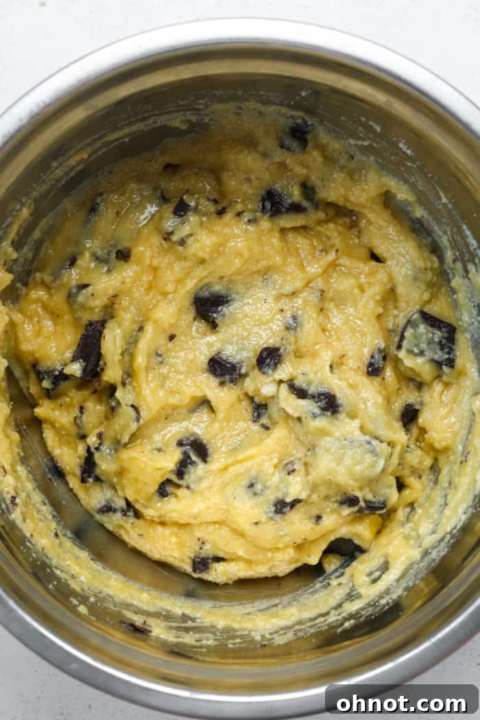 Muffin batter with generous chocolate chunks folded in, ready to be scooped into the muffin pan.