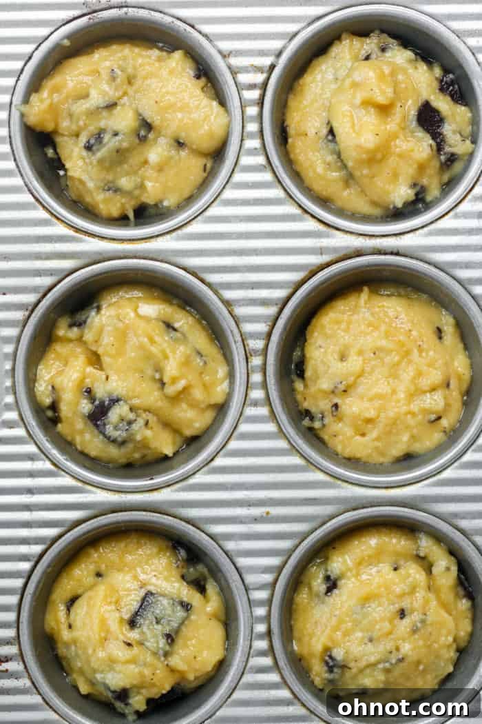 Raw grain-free muffin batter perfectly portioned into a muffin pan, topped with extra chocolate chips.