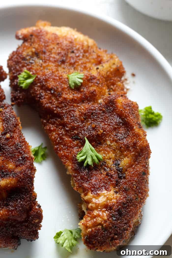 Crispy chicken schnitzel on a plate, garnished with fresh lemon, ready for serving.