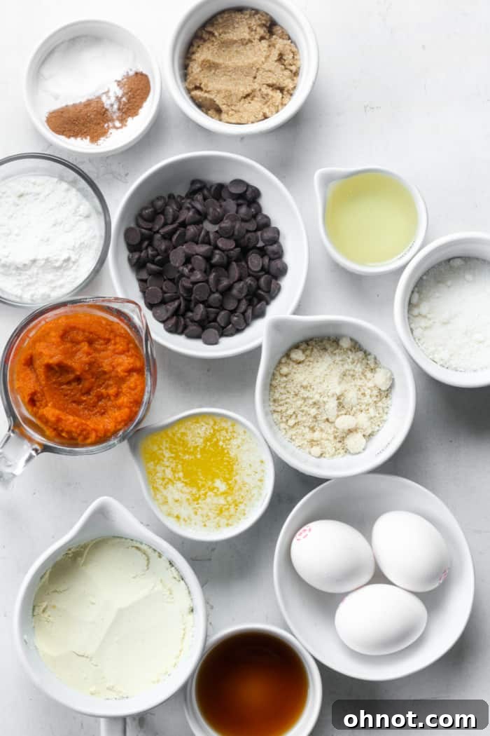 Assortment of dry and wet ingredients including canned pumpkin, flours, and spices, ready for mixing healthy pumpkin bars.