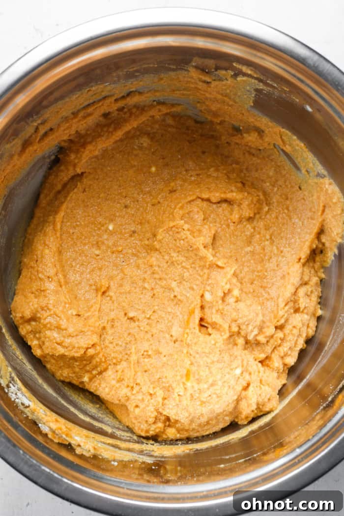Rich orange pumpkin bar batter in a mixing bowl before adding chocolate chips.