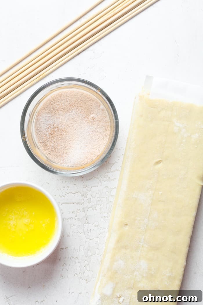 Fresh puff pastry dough alongside a bowl of melted butter, ready for baking.