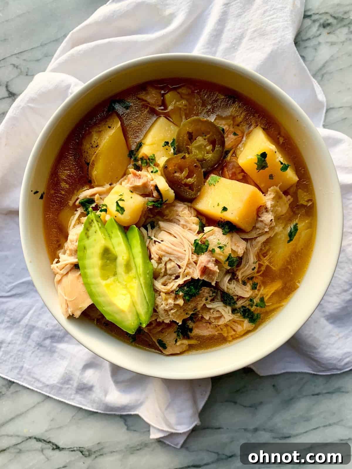 Delicious Whole30 White Chicken Chili in a bowl with avocado and jalapeño garnish.