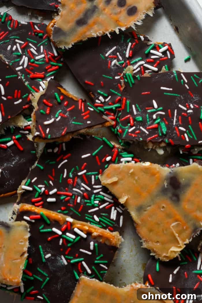 Crunchy, creamy, and chocolaty pretzel crack bark scattered on a festive background.