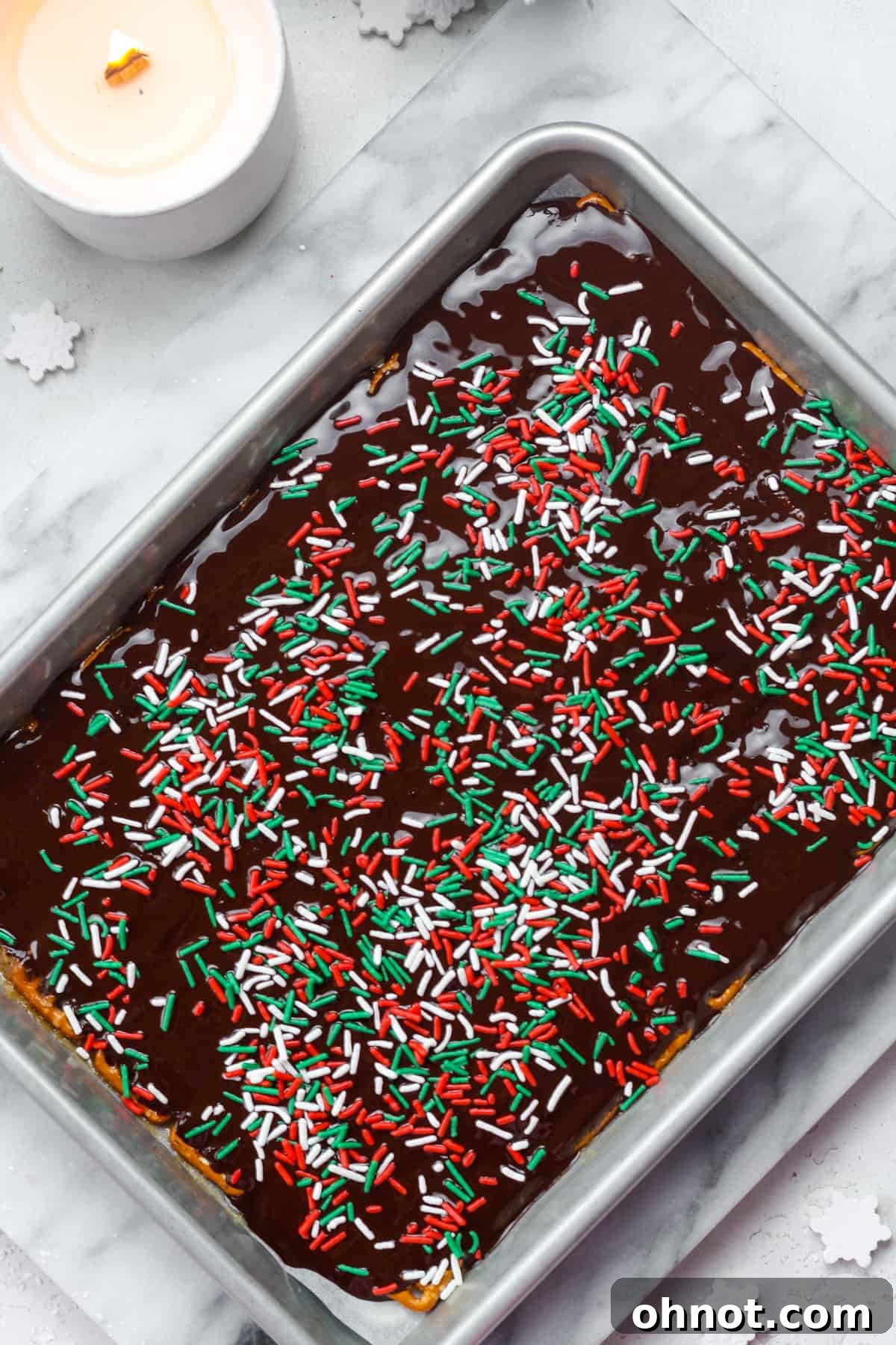 Festive Christmas holiday sprinkles generously scattered over the melted chocolate layer.