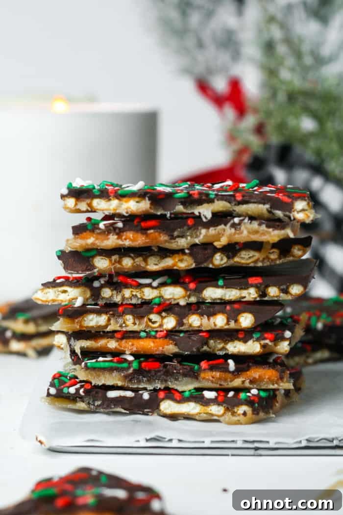 Various pieces of holiday pretzel crack bark with sprinkles on a white surface.
