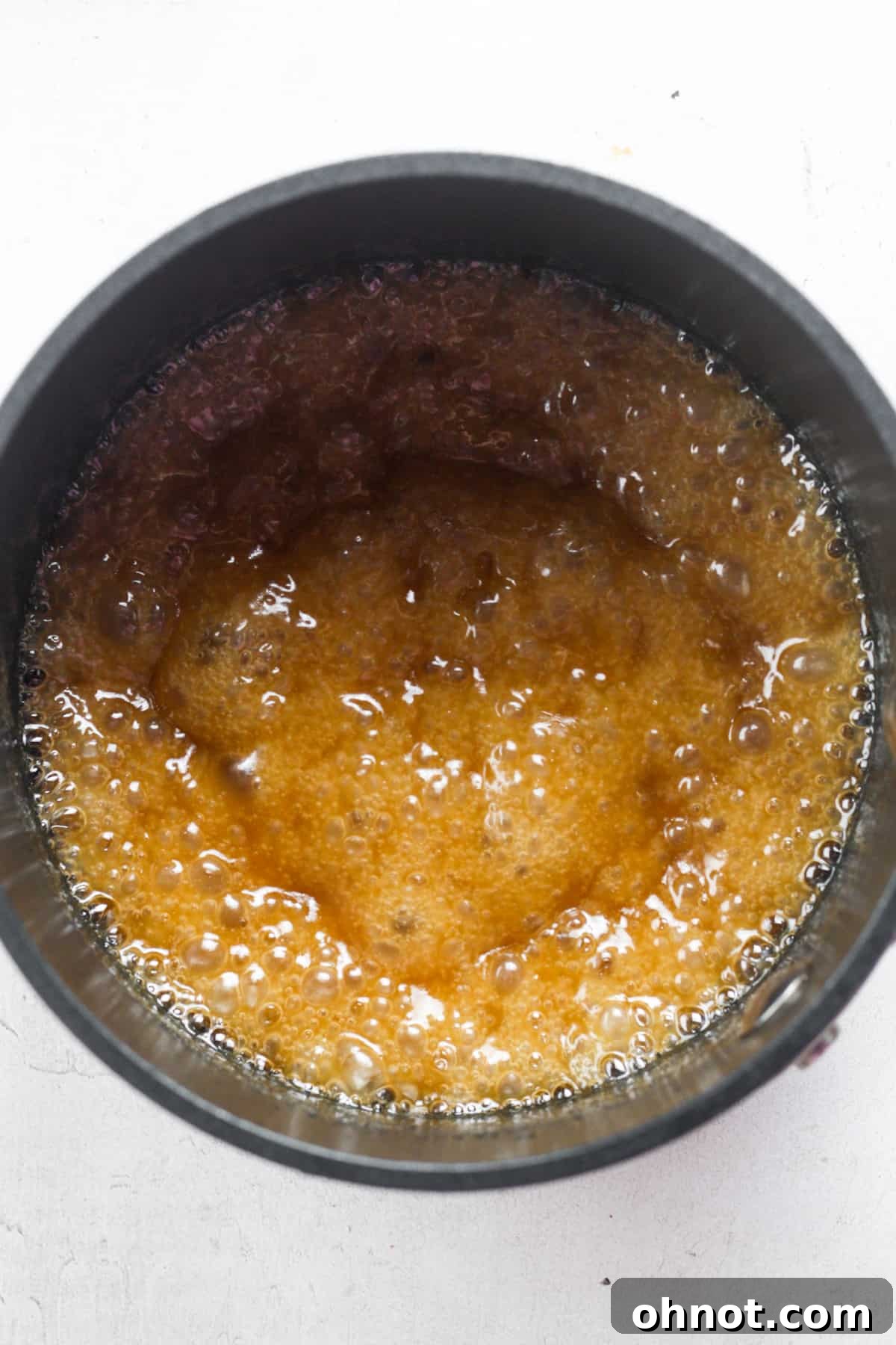 Close-up of bubbling homemade caramel sauce cooking in a saucepan.