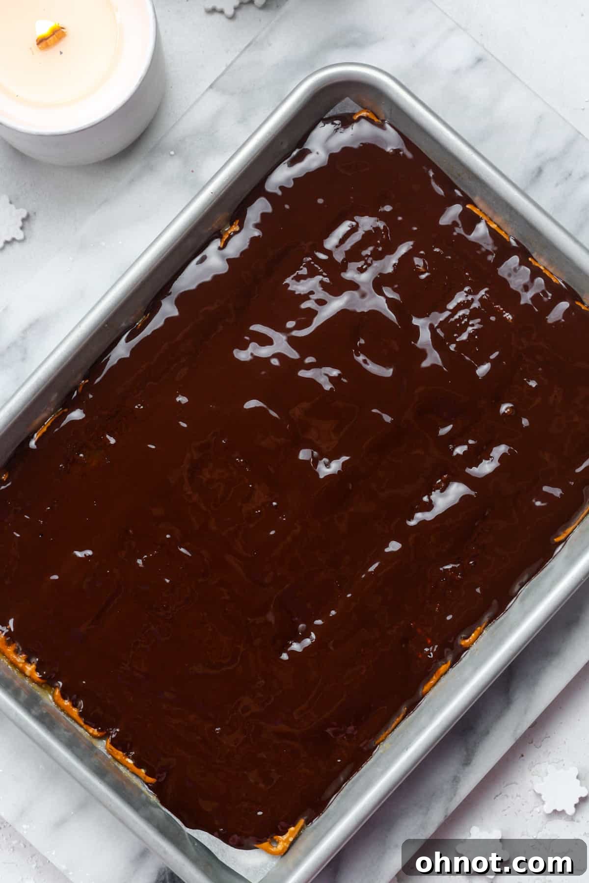 Smooth, melted chocolate spread evenly over the pretzel and caramel base in a baking pan.