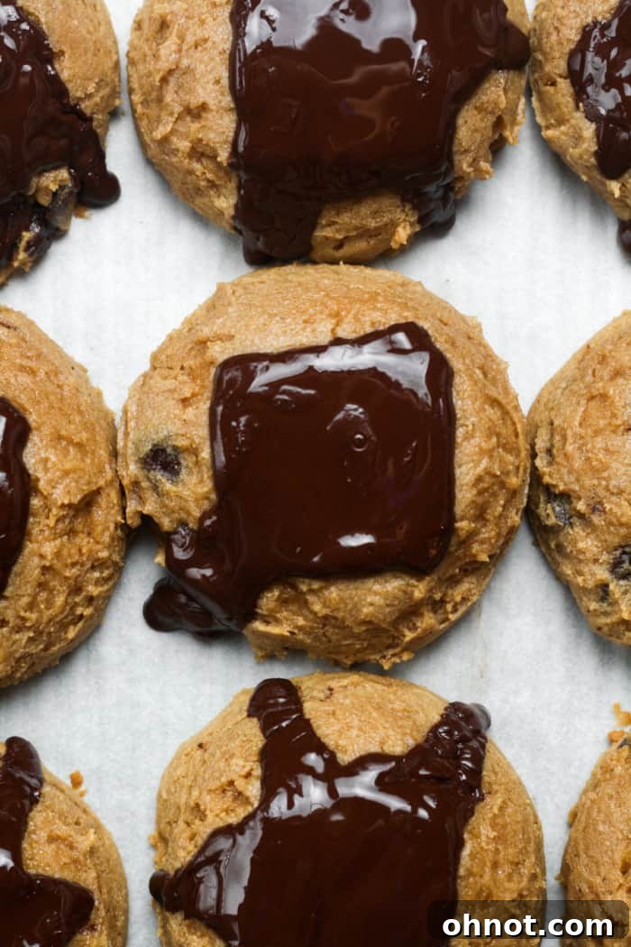 Freshly baked sourdough chocolate chip cookies with melted chocolate, still on the baking sheet.