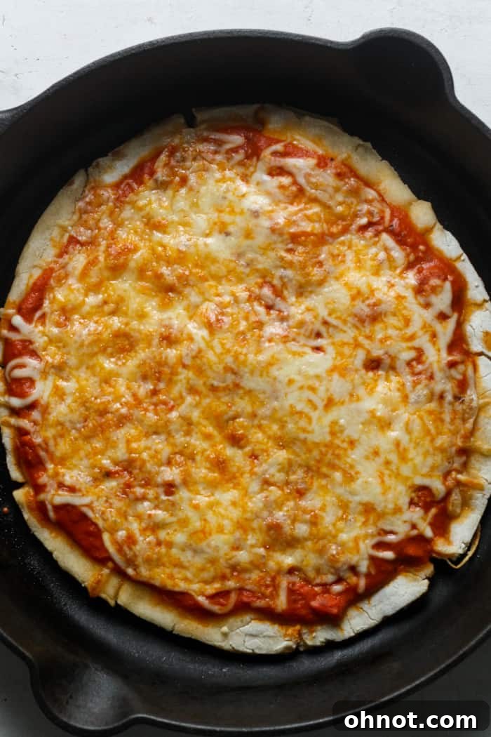 A perfectly baked sourdough pizza crust, topped with melted cheese and delicious ingredients, fresh from the oven.
