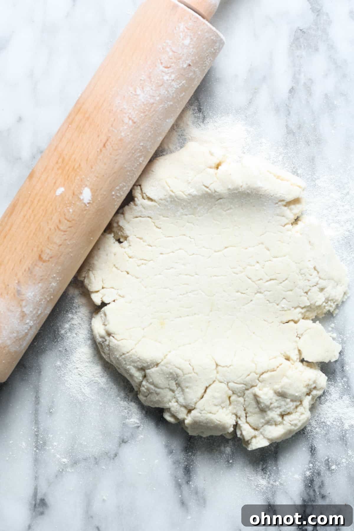 A rolling pin in action, gently flattening the sourdough pizza dough on a floured surface.