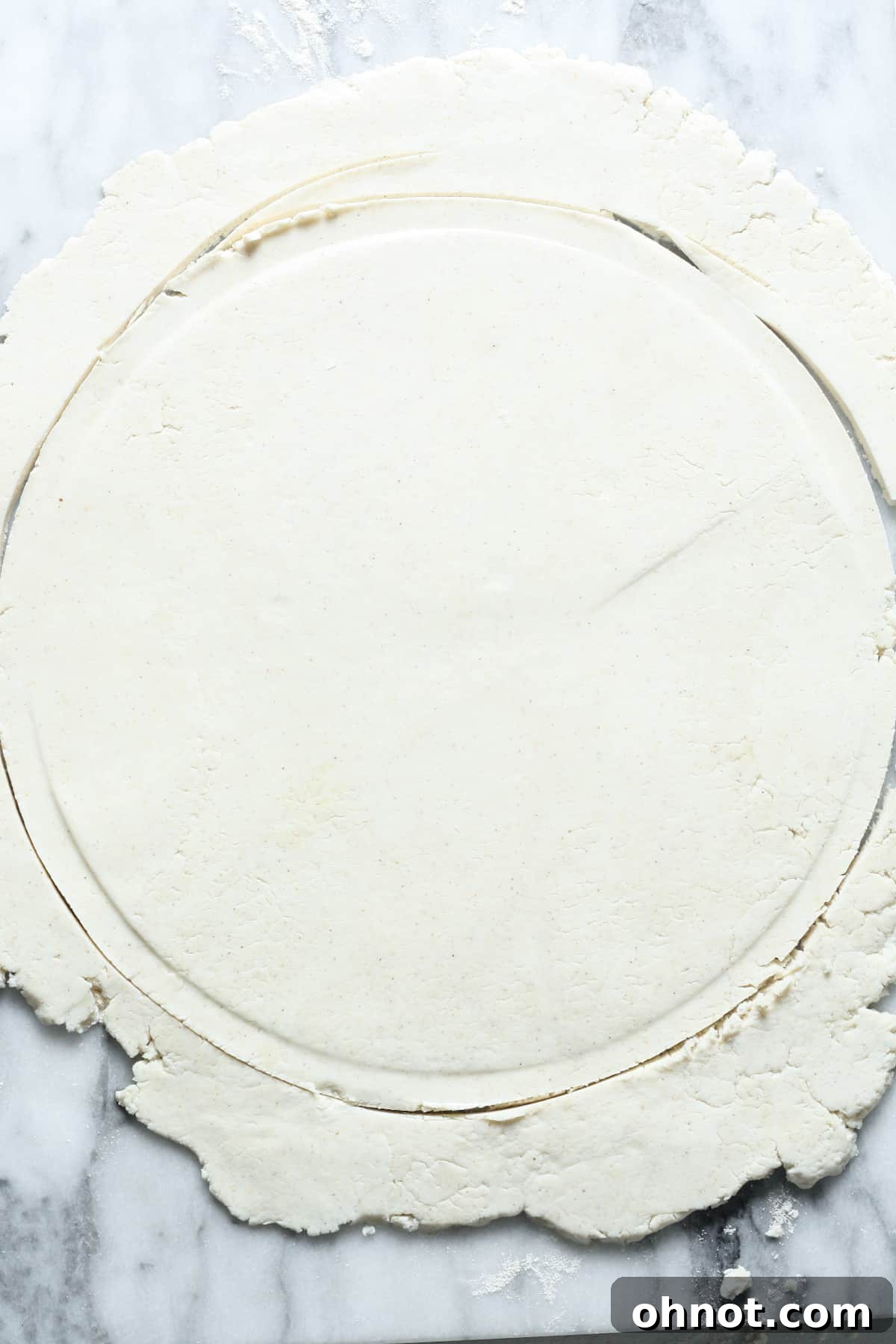 A perfectly round, thin circle of sourdough pizza dough on a floured surface, awaiting its transfer to the hot skillet.