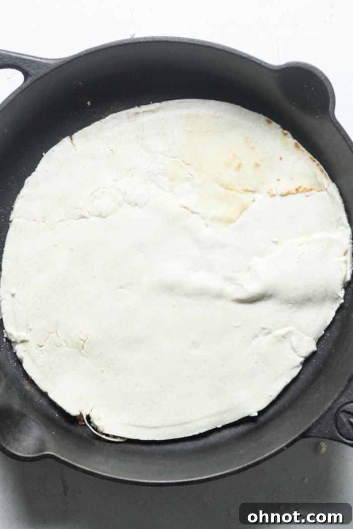 The rolled-out pizza dough carefully placed into the hot cast iron skillet, ready for initial cooking.