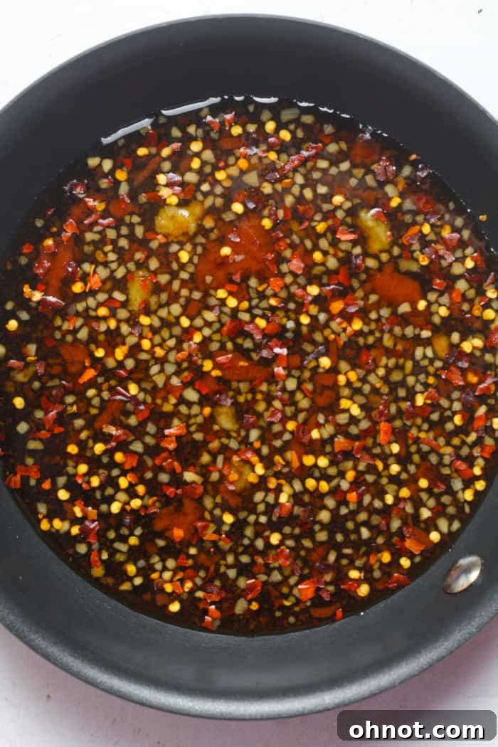 All ingredients except cornstarch simmering in a skillet, with visible red pepper flakes.