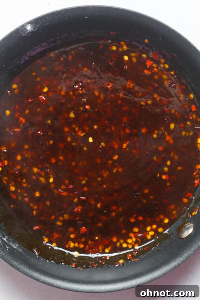 A close-up shot of the sticky, sweet, and spicy sauce simmering in a pan, thickening beautifully.