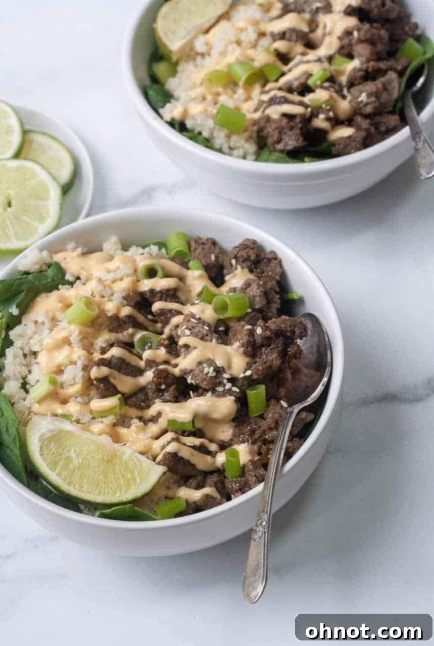Close-up of a serving of Whole30 Korean Beef Bowl, showcasing the rich beef, cauliflower rice, and fresh garnishes.