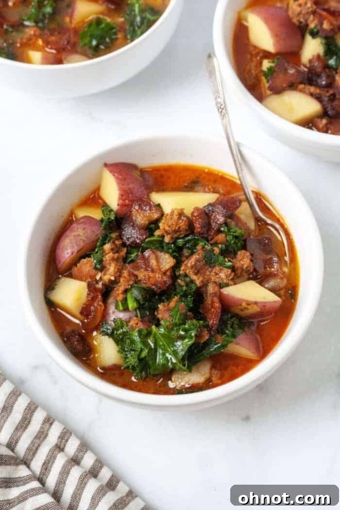 Whole30 Zuppa Toscana in white bowl with spoon, garnished with fresh kale.