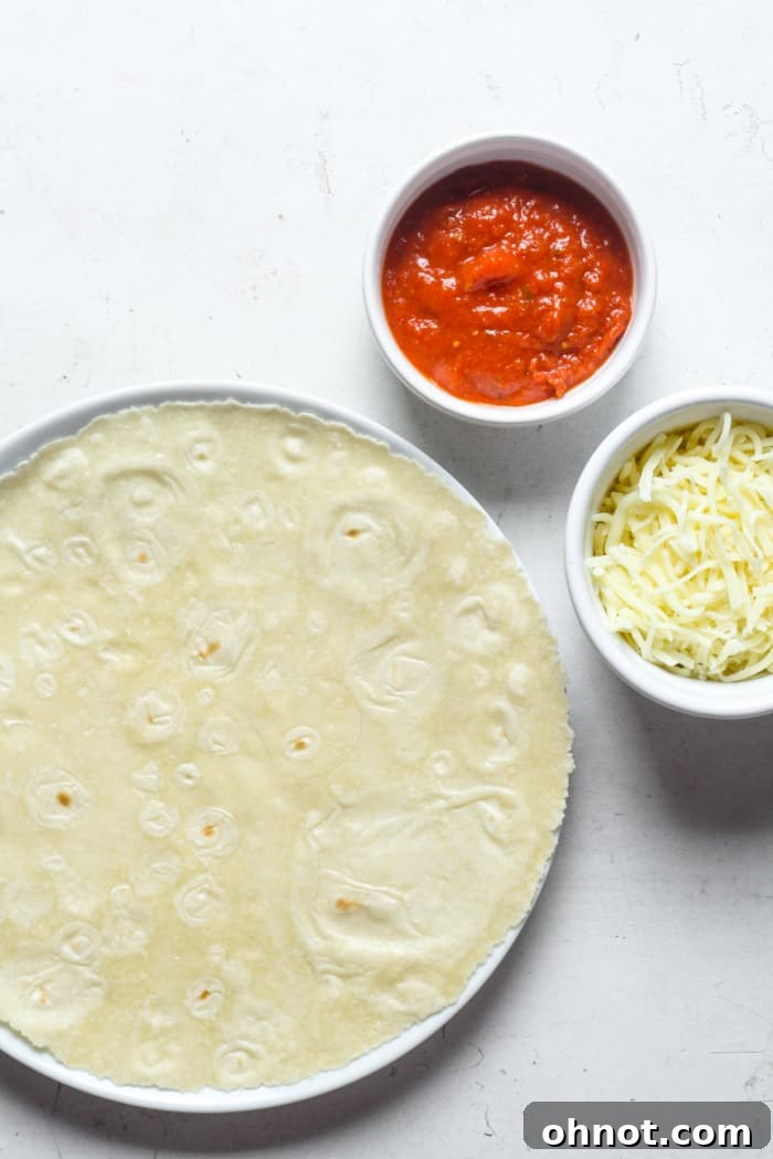 A tortilla with pizza sauce and shredded cheese, ready for toppings.
