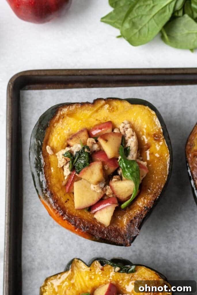 Sausage stuffed acorn squash halves with diced apples, showcasing the hearty filling.