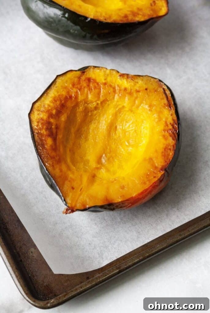 Perfectly roasted acorn squash halves on a baking pan, golden and ready for stuffing.