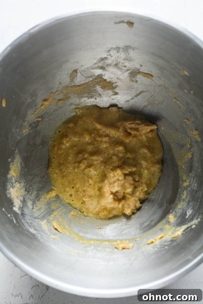 Gooey cookie dough with egg and vanilla added in the mixer bowl.