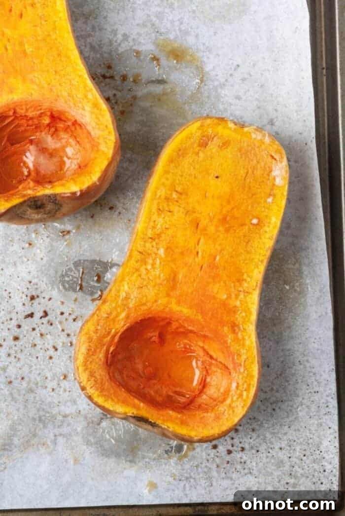 Raw butternut squash halves on a baking sheet, ready for roasting.