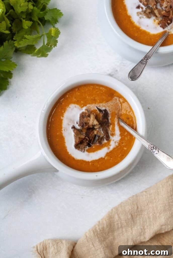 A bowl of Whole30 butternut squash soup topped with coconut milk swirl and crispy bacon.