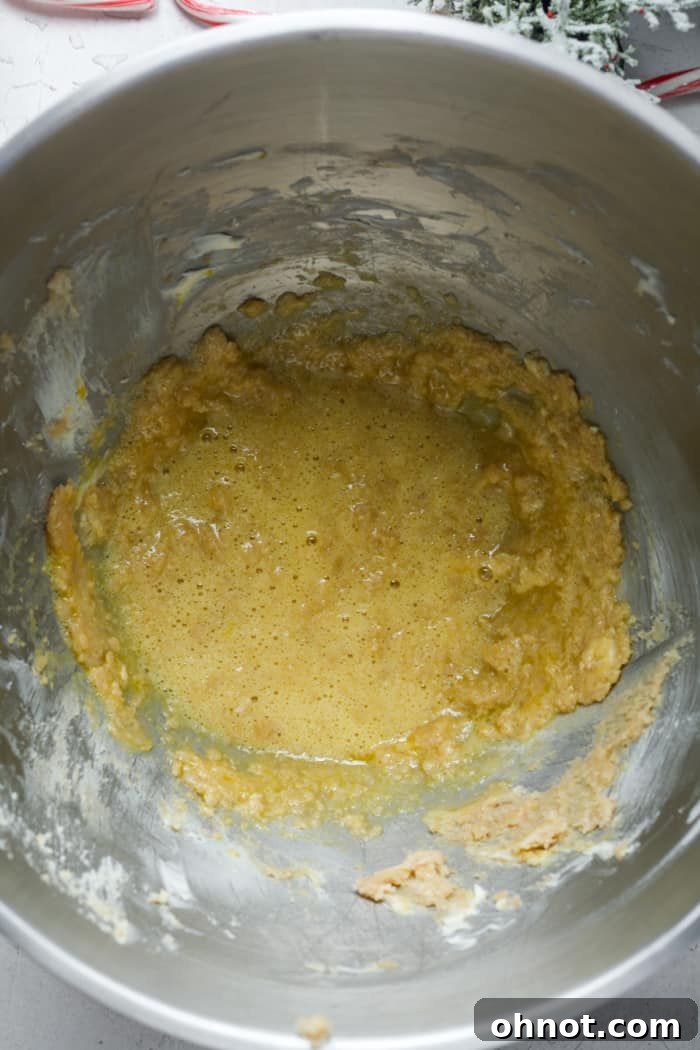 Gooey mixture of butter, sugar, and egg in a mixing bowl after combining wet ingredients.