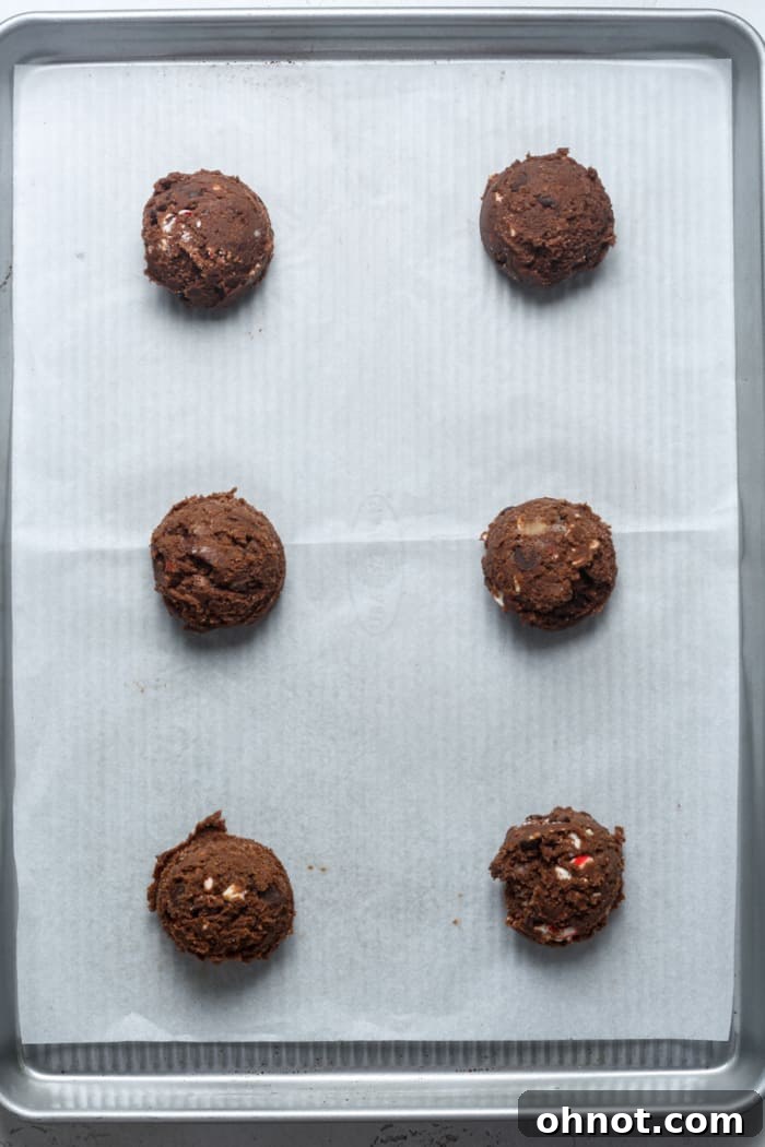 Evenly scooped balls of chocolate cookie dough placed on a parchment-lined baking sheet.