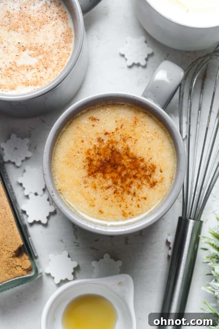 A warm, cozy glass of vegan eggnog with a cinnamon stick, perfect for chilly weather.
