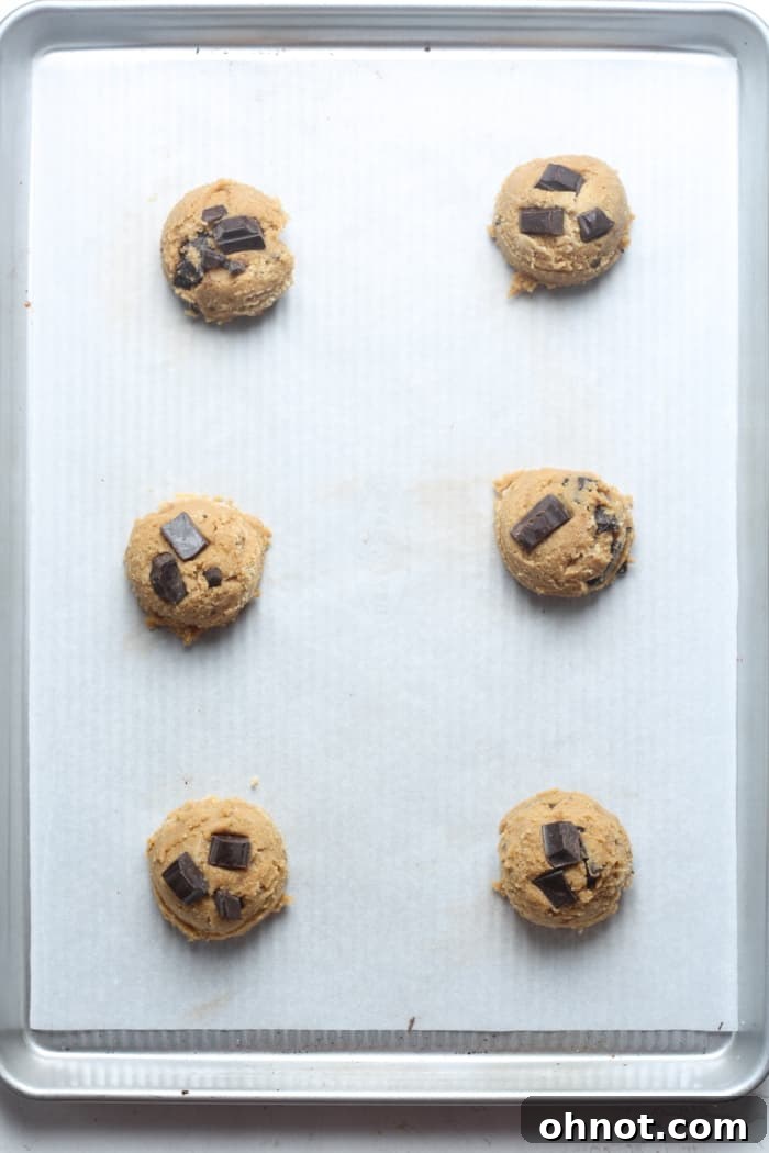 Balls of healthy cookie dough on a parchment-lined baking pan.