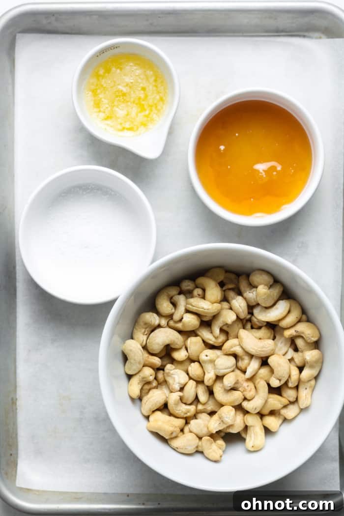 Four simple ingredients: cashews, a jar of honey, a block of butter, and a sprinkle of sea salt, ready for preparation.