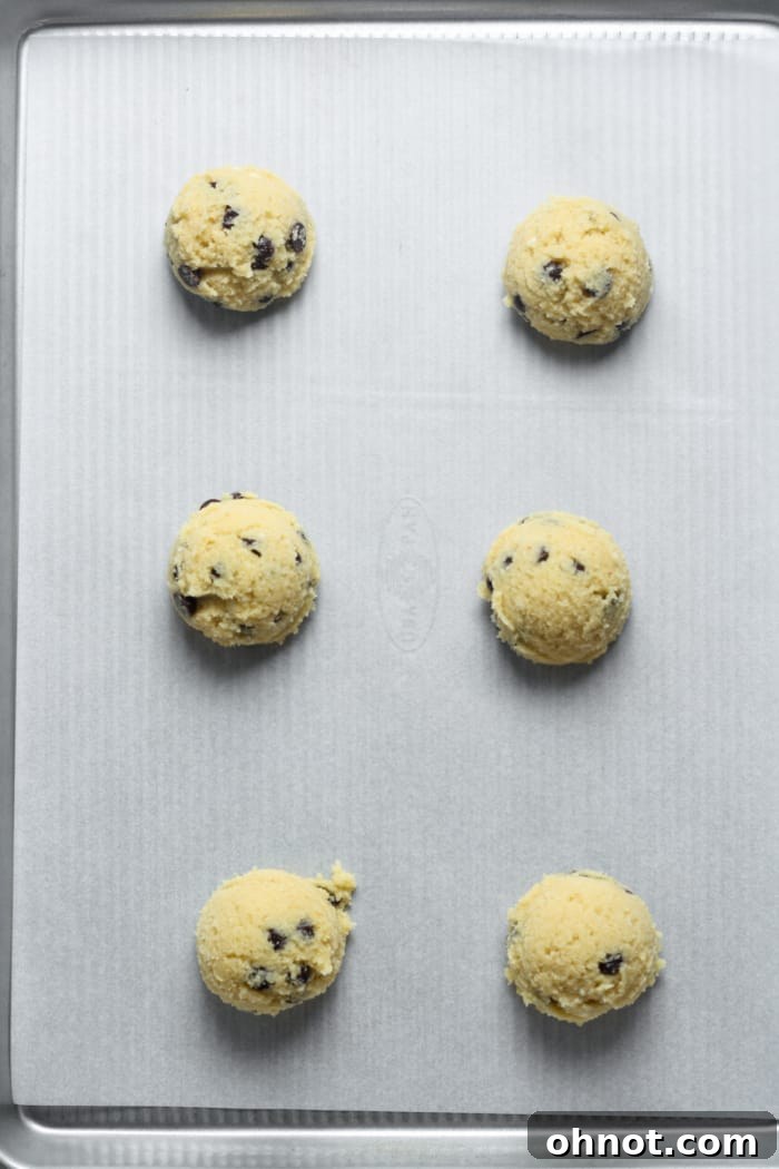 Scoops of healthy cookie dough placed on a parchment-lined baking sheet.