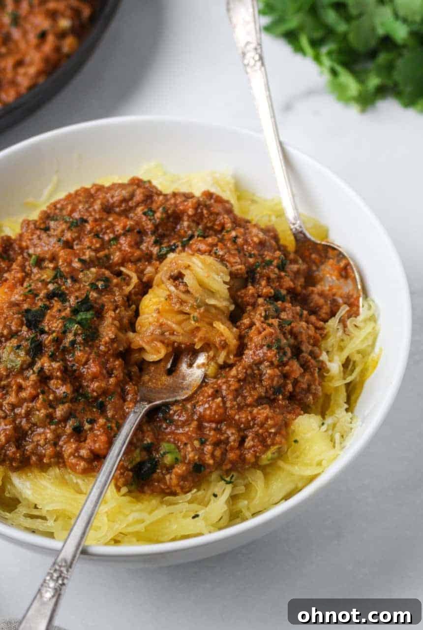 Delicious baked spaghetti squash strands served with a rich meat marinara sauce, garnished with fresh herbs.
