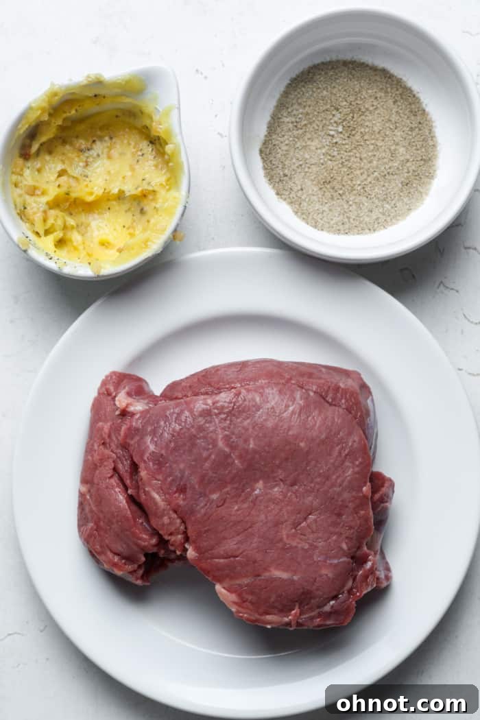 Raw filet mignon seasoned with salt and pepper, alongside softened butter and minced garlic.