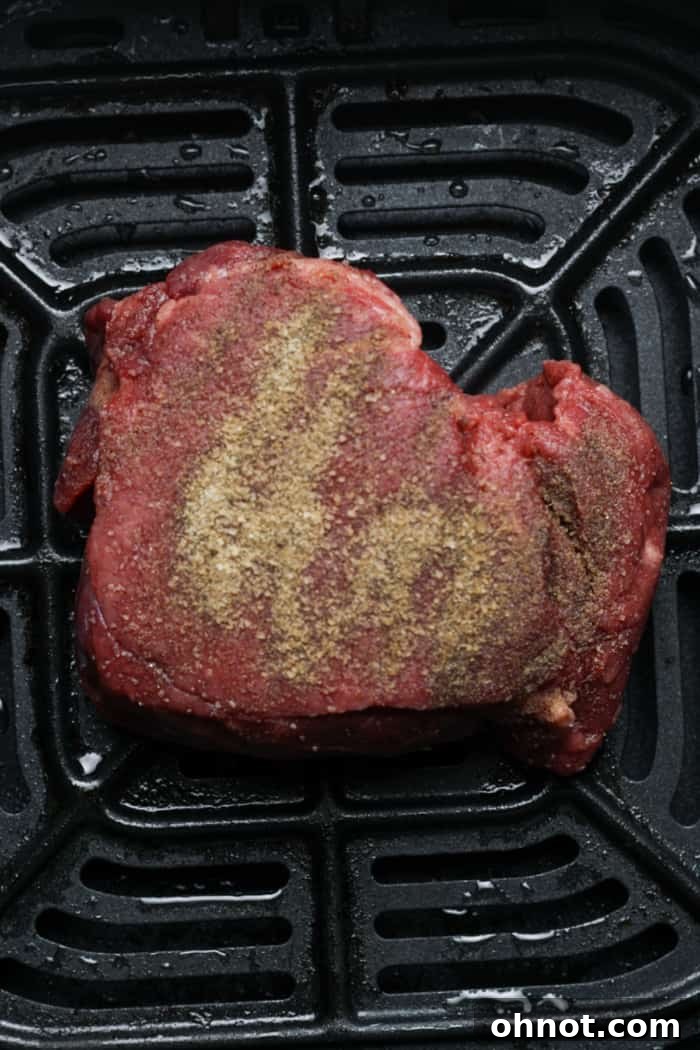 Filet mignon cooking inside an air fryer basket.