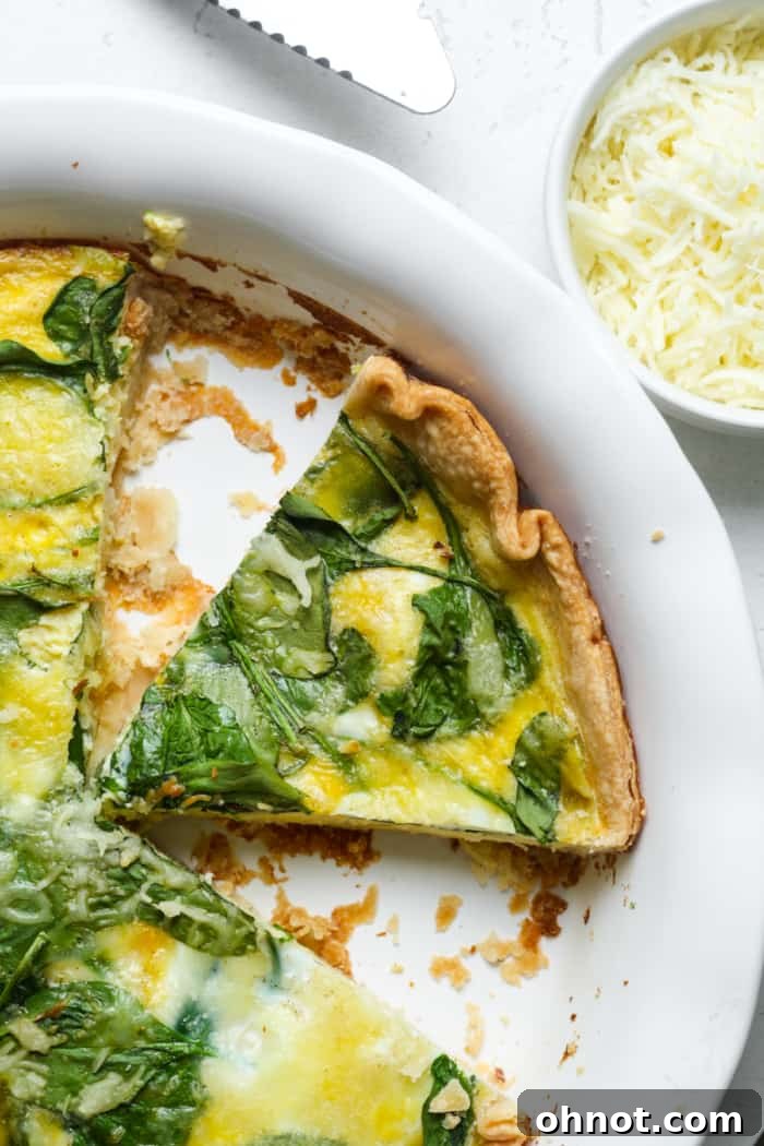 A perfect slice of Quiche Florentine, showing the flaky crust, creamy egg and spinach filling, and melted cheese, ready to be enjoyed.