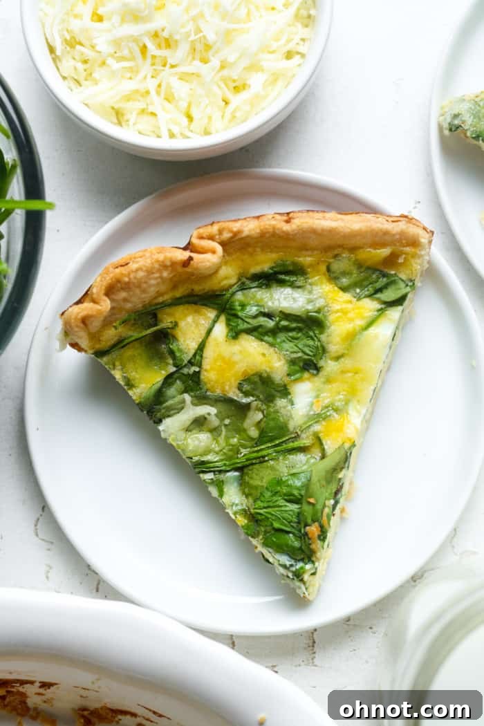 A close-up of a slice of Quiche Florentine, highlighting the perfectly baked egg custard and golden crust texture.