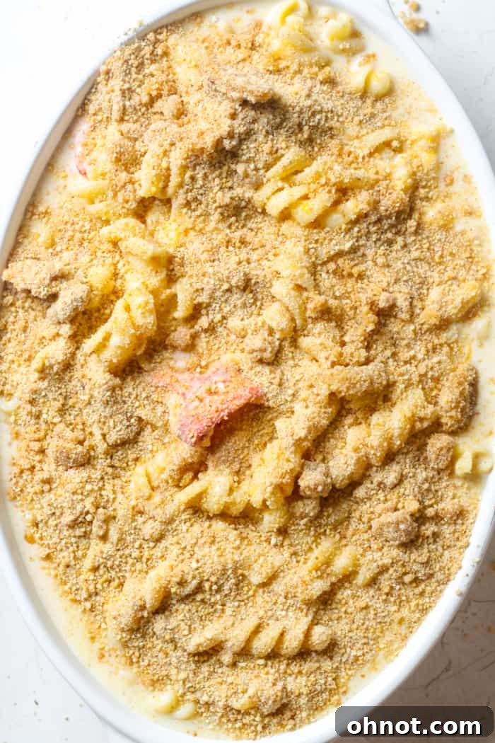 The lobster mac and cheese mixture in a baking dish, generously topped with golden breadcrumbs.