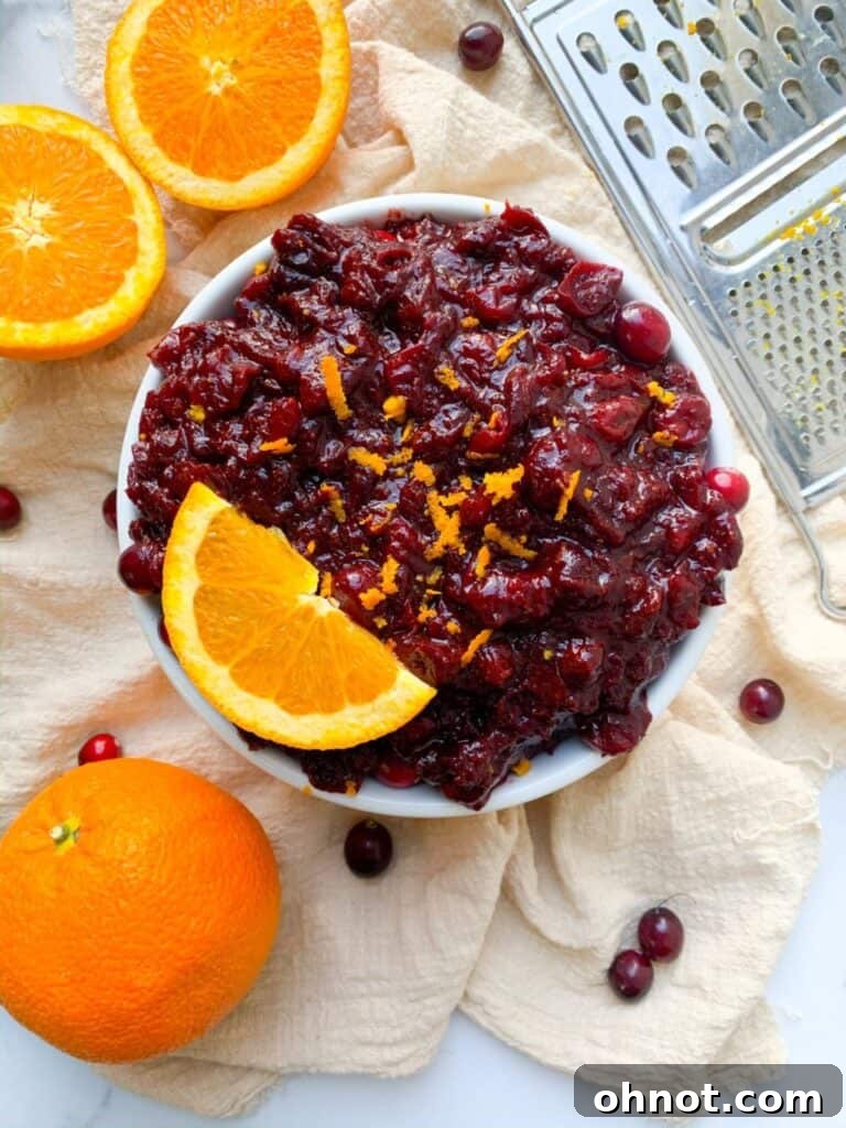 Paleo cranberry sauce in a bowl with sliced orange garnish, highlighting its fresh and vibrant appearance