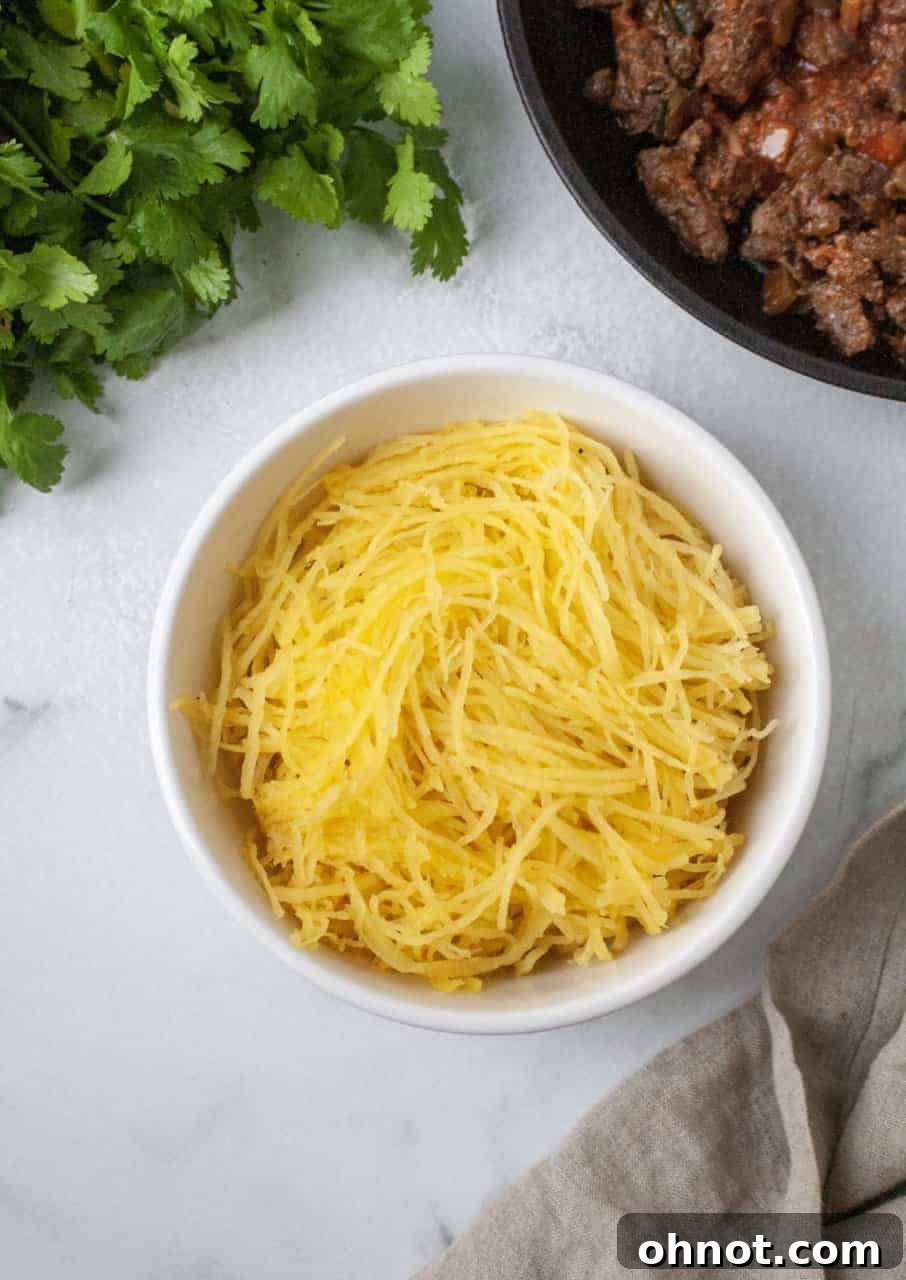 Spaghetti squash halves ready for roasting, showing scooped out seeds and a light coating of coconut oil.