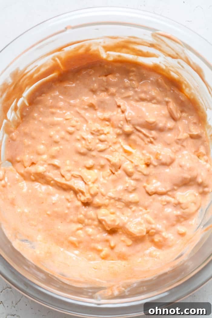 A large bowl showcasing the creamy, spicy base of the dip, perfectly mixed and ready for the next ingredients.