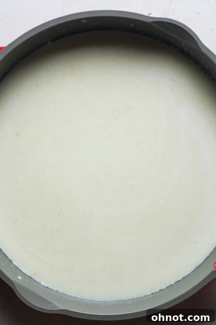 Whole milk being poured into the roux in a skillet, ready to be combined.