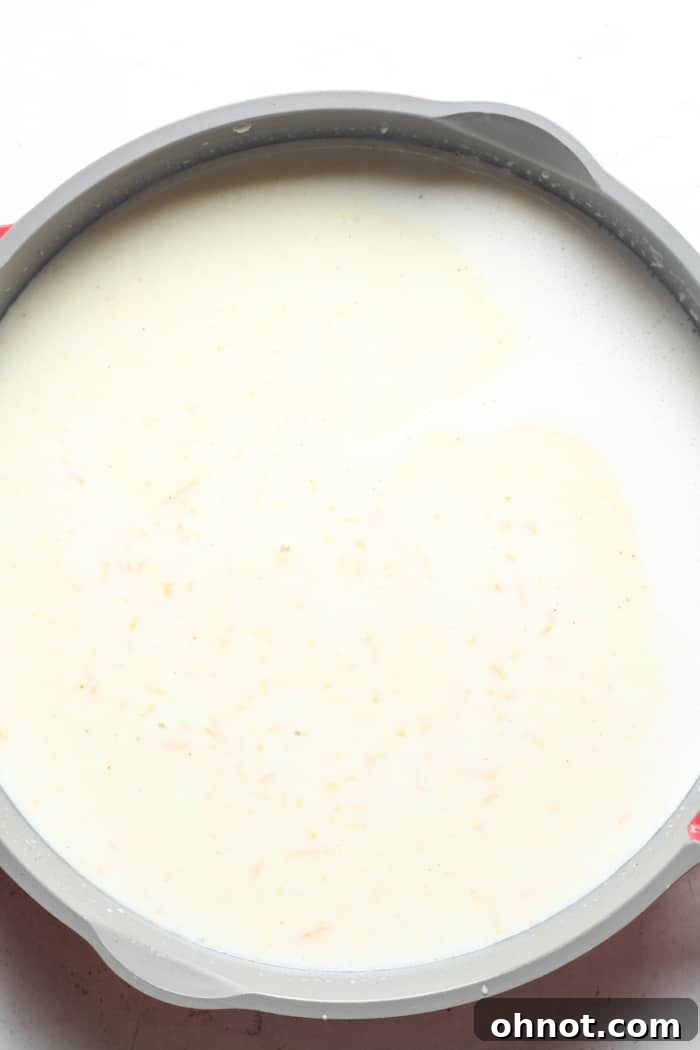 Creamy cheese sauce thickening in a skillet after adding cheeses and seasonings.